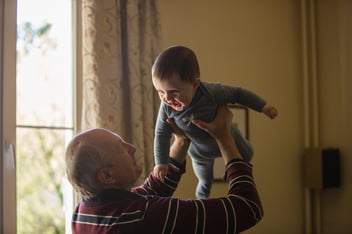 Older man hold up an infant 